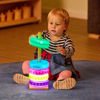 Bebé a brincar com brinquedo de empilhar anéis coloridos