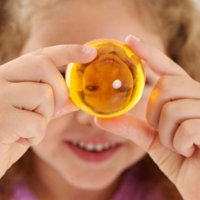 Menina segura esfera amarela transparente refletindo o rosto