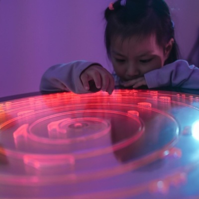 Criança a brincar com jogo labirinto iluminado em plástico transparente.