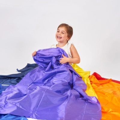 Criança com tecidos coloridos grandes no chão