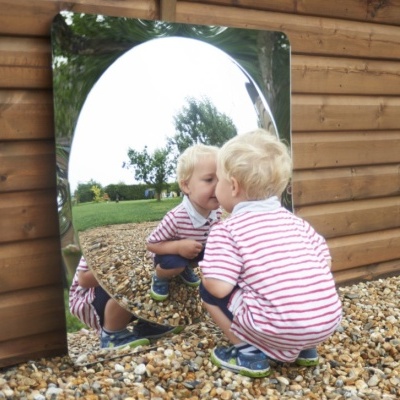 Criança loira em camisola às riscas refletida num espelho junto a parede de madeira