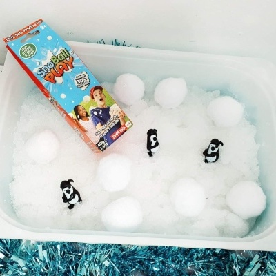 Caixa branca com bolas de neve artificiais e pinguins pequenos, caixa Snowball Play ao lado