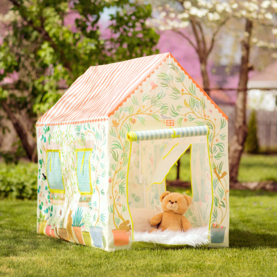 Tenda infantil em tecido floral com urso de peluche no interior num relvado verde