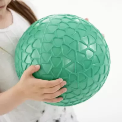 Bola verde texturizada segurada por criança com vestido branco