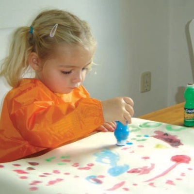 Criança a pintar com tintas coloridas numa folha grande de papel
