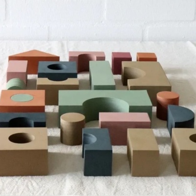 Blocos de madeira coloridos com formas geométricas sobre superfície branca texturada