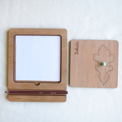 Conjunto de tábuas de madeira claras com moldura para papel e desenho de folha com texto 'Le Belada'