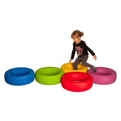 Criança a brincar em pneus de borracha coloridos