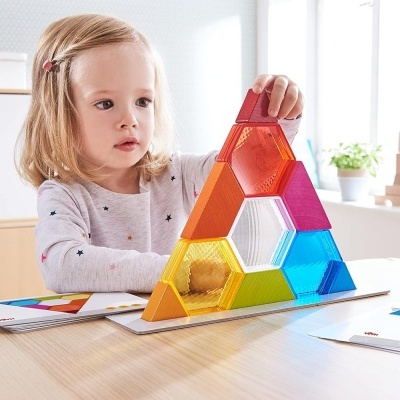 Criança a brincar com blocos de montar coloridos numa mesa branca