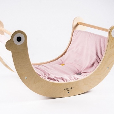 Baloiço de madeira com almofada rosa e olhos desenhados nas extremidades