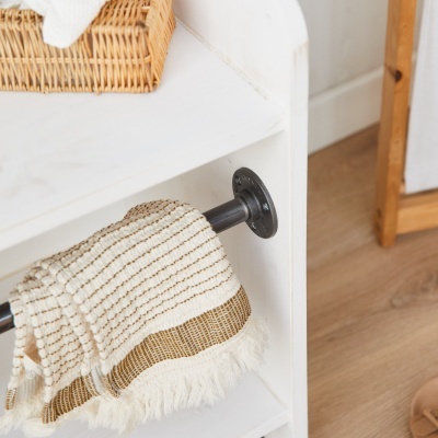 Estante branca de madeira com barra metálica preta e têxtil decorativo bege com padrão e franjas