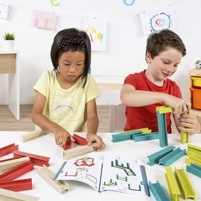 Duas crianças brincam com blocos de construção coloridos numa mesa branca