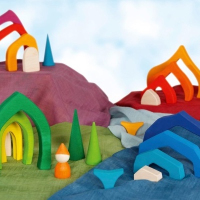 Brinquedos de madeira coloridos com formas arredondadas e cónicas sobre tecidos coloridos