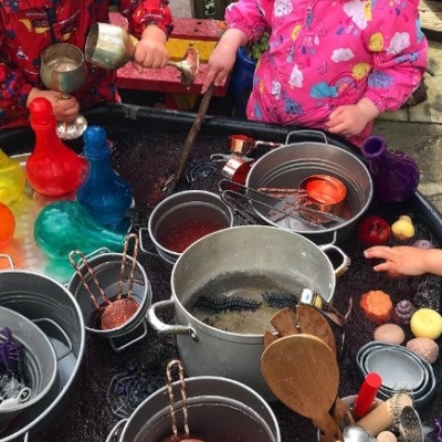 Utensílios de cozinha e brinquedos coloridos com crianças a brincar ao ar livre