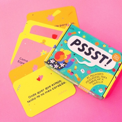 Caixa ilustrada colorida com cartas amarelas e rosa sobre fundo rosa