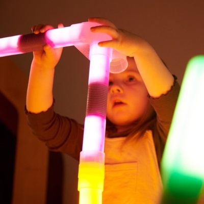 Criança a segurar brinquedo de tubos LED coloridos