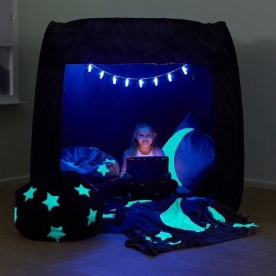 Tenda de descanso preta com luzes LED azuis, almofadas com padrões de estrelas e lua brilhantes, e uma criança dentro da tenda.