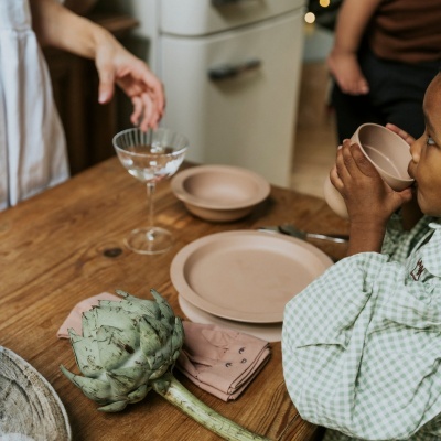 Conjunto de loiça castanha em mesa de madeira com alcachofra e taça de vidro