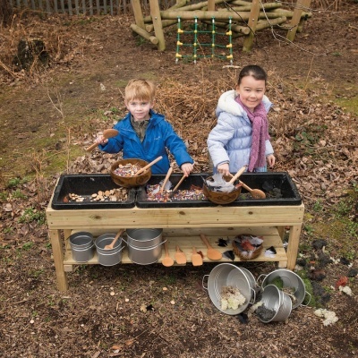 Bancada de brincadeira em madeira com crianças e utensílios ao ar livre