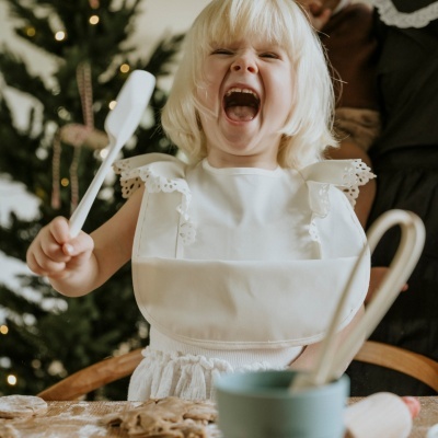 Criança loira com vestido branco brincando na cozinha decorada para o Natal