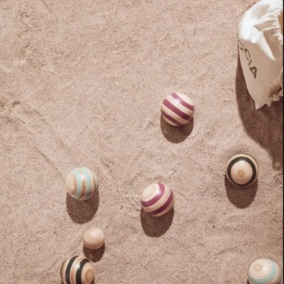 Bolas coloridas listradas para jogo na areia com saco branco marcado próximo