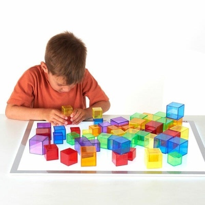 Cubos coloridos translúcidos de plástico sobre mesa branca iluminada