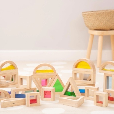 Blocos de construção em madeira com peças transparentes coloridas num tapete claro