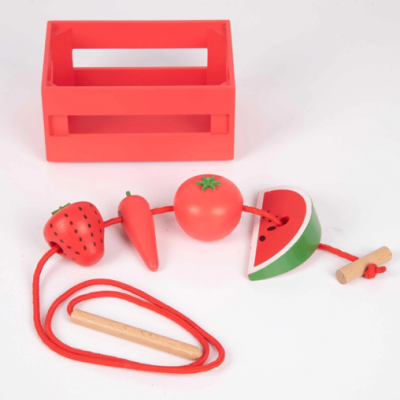 Brinquedo de enfiar com peças de frutas e legumes coloridos, cordão vermelho e caixa vermelha.