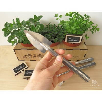 Ferramenta de jardinagem em metal com vasos de plantas aromáticas e etiquetas num suporte de madeira