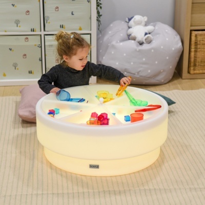 Mesa infantil redonda iluminada com cubos coloridos e criança a brincar