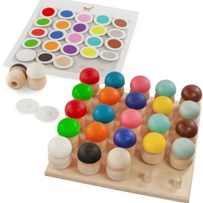 Jogo de tabuleiro de madeira com peões coloridos e embalagem ao fundo com círculos coloridos.