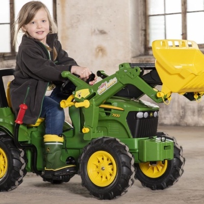 Trator de brinquedo verde e amarelo com criança sentada a brincar