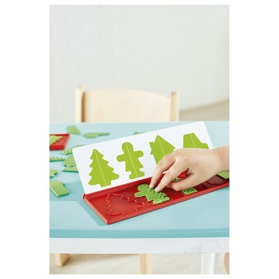 Jogo de puzzle com peças verdes e base vermelha numa mesa azul clara