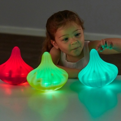 Luminárias de silicone em três cores com luzes LED e uma menina a brincar com elas
