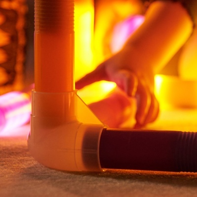 Tubos de plástico em ângulo com mão de criança ao fundo em ambiente iluminado quente