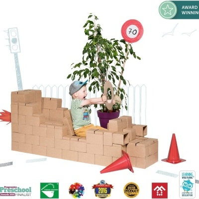 Criança num veículo construído com blocos de cartão e elementos de trânsito num ambiente branco