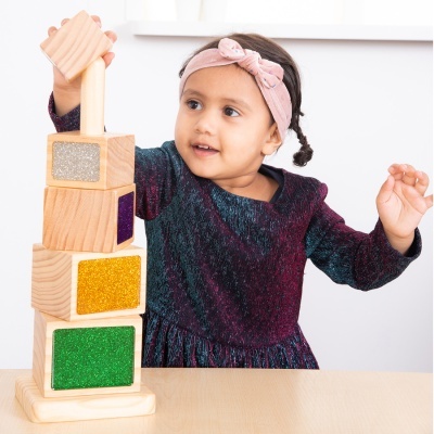 Criança a brincar com blocos de madeira coloridos brilhantes