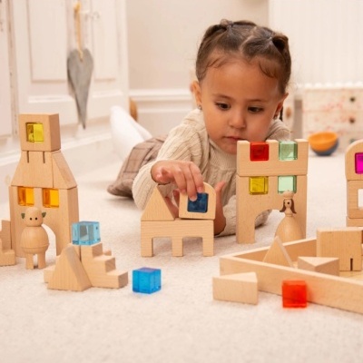 Criança a brincar com blocos de madeira coloridos no chão