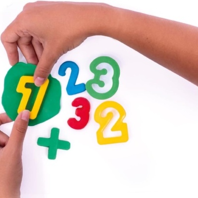 Mãos segurando números e sinal de mais coloridos em plástico sobre fundo branco