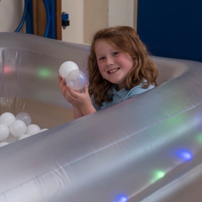 Piscina insuflável transparente com luzes LED e bolas brancas com criança sorridente