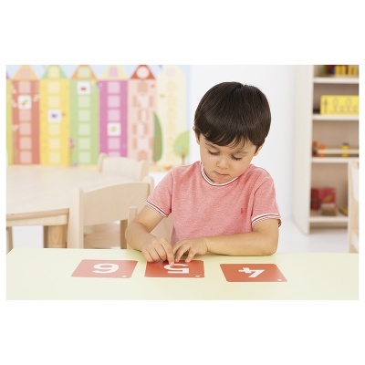 Criança a brincar com cartões numéricos vermelhos numa sala de jogo educativa