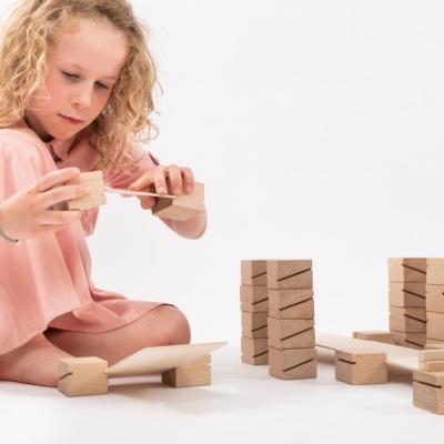 Criança a brincar com blocos de madeira empilhados num fundo branco