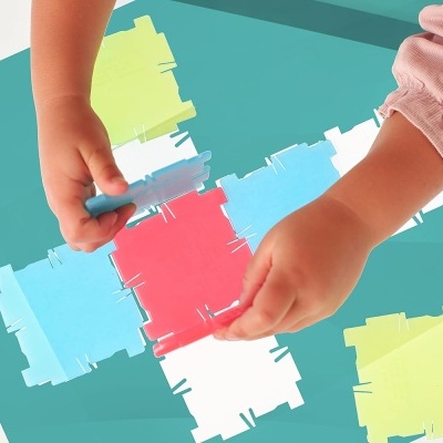 Mãos de criança montando puzzle colorido em superfície verde