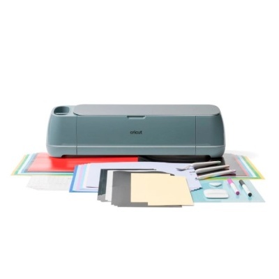 Máquina de corte Cricut com acessórios e papéis coloridos sobre fundo branco