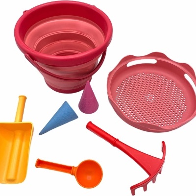 Conjunto de brinquedos de praia coloridos em plástico incluindo balde dobrável, peneira, ancinho, pá e moldes cónicos.