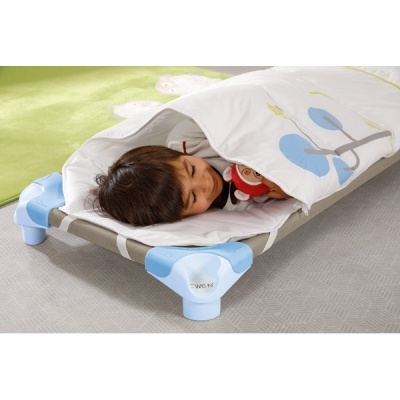 Criança deitada em cama infantil com saco de dormir branco e estrutura azul e cinza