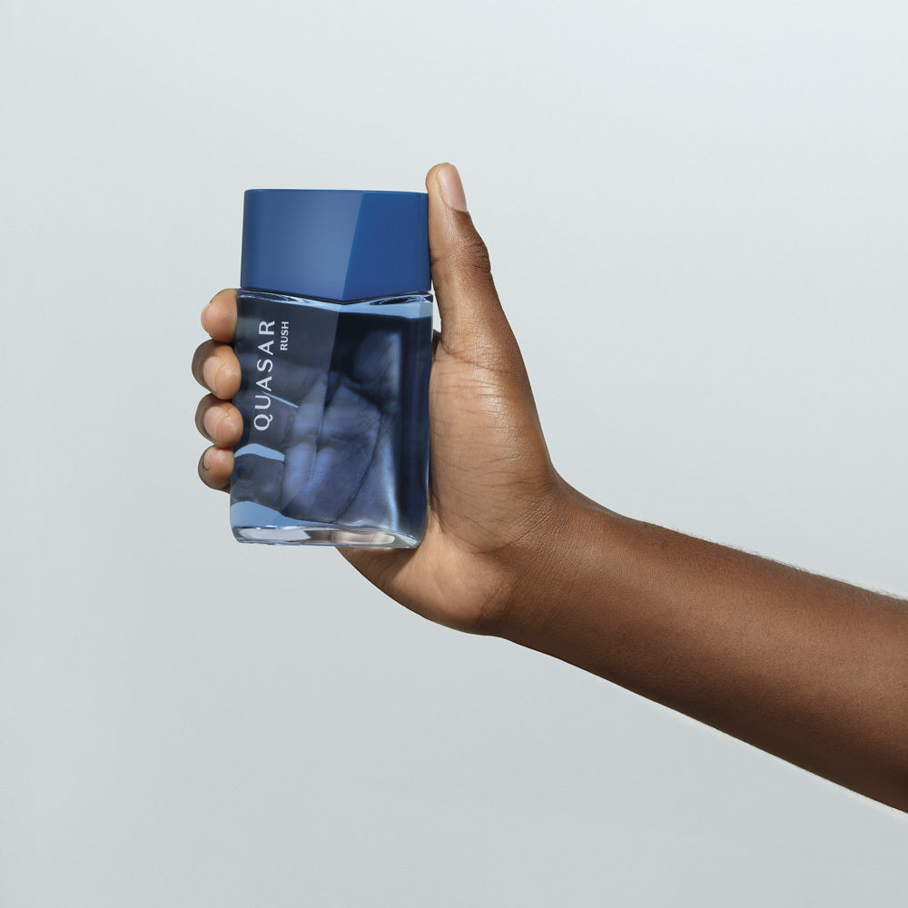 Frasco de perfume azul seguro por mão contra fundo cinza