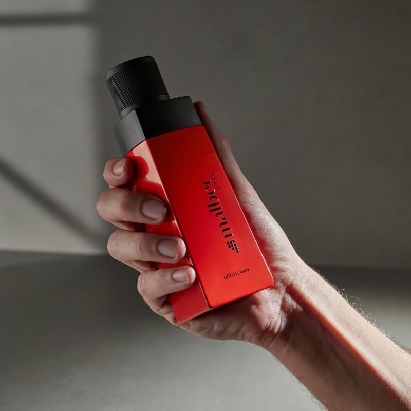 Malbec Sport Eau de Toilette 100ml Frasco de perfume vermelho com tampa preta segurado por uma mão