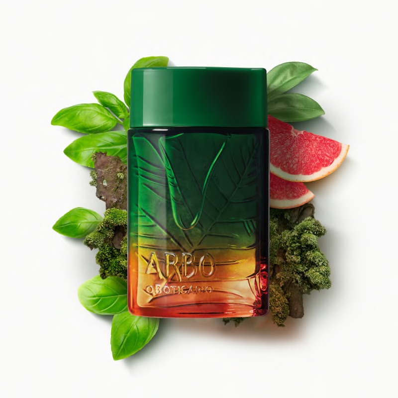 Arbo Liberté Eau de Toilette 100ml Frasco verde e âmbar de perfume com tampa verde escura entre folhas e frutas