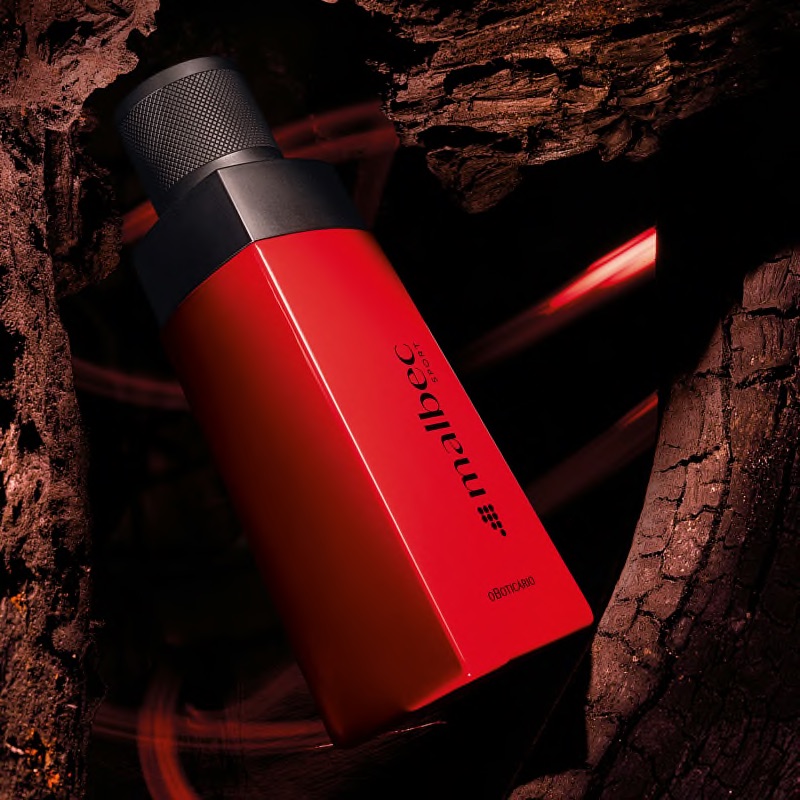 Malbec Sport Eau de Toilette 100ml Frasco de perfume vermelho com tampa preta e texto impresso, sobre fundo de madeira escura.